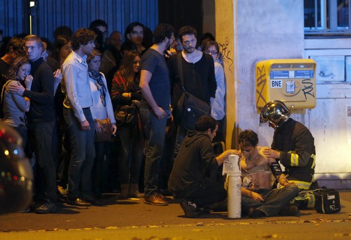 ATTENTION EDITORS - VISUAL COVERAGE OF SCENES OF INJURY OR DEATH  A member of the French fire brigade aids an injured individual near the Bataclan concert hall following fatal shootings in Paris, France, November 13, 2015. At least 30 people were killed in attacks in Paris and a hostage situation was under way at a concert hall in the French capital, French media reported on Friday.  REUTERS/Christian Hartmann