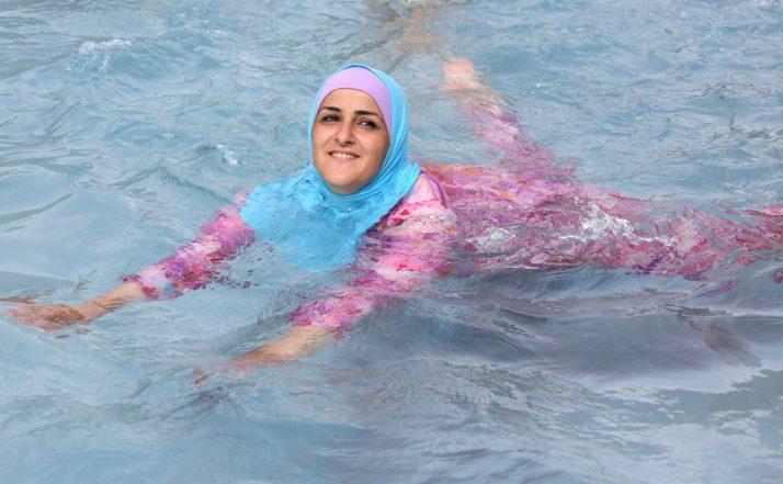 epa03366113 A young Turkish woman cools off while wearing a burkini at an open-air bath in Berlin, Germany, 20 August 2012. EPA/STEPHANIE PILICK