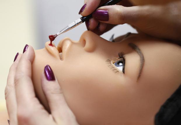 Raphaela, an employee at the Dreamdoll company, works on the makeup of a silicone dream doll in their workshop in Duppigheim near Strasbourg, December 2, 2014. The realistic silicone sex dolls can be ordered from a catalogue based on four hair and eye color models for a base price of 5,500 euros ($6,150). The dolls weigh around 40 kilos due to a lightweight aluminum structure and take a week to construct. The company of three employees produces some one hundred custom-made silicone sex dolls a year, mainly for European customers. Picture taken December 2, 2014. REUTERS/Vincent Kessler (FRANCE - Tags: SOCIETY BUSINESS TPX IMAGES OF THE DAY) - RTR4S7W5
