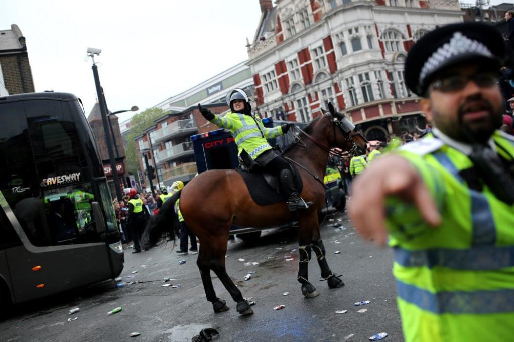 LONDON, ENGLAND - MAY 10: Police try to control West Ham fans gathered near 'The Champions' statue outside the Boleyn Ground on May 10, 2016 in London, England. Tonights Premier League match against Manchester United is West Ham United's last game at the Boleyn Ground, bringing to an end 112 years of the club's history at the ground. The club will move into the Olympic Stadium next season, making way for developers and plans for 800 new homes where the stadium now stands. (Photo by Dan Kitwood/Getty Images)