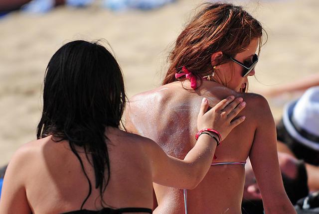 A woman spreads sunscreen on the back of a friend at the Renaca beach in Vina del Mar, on January 24, 2009. Solar radiation, the principal cause of the skin cancer, has made the disease increase over 100% in the last 10 years in Chile. The National Cancer Corporation (CONAC) initiated a campaign this summer, aimed particularly at children, to raise awareness about the harm caused by ultraviolet radiation. AFP PHOTO/Martin Bernetti (Photo credit should read MARTIN BERNETTI/AFP/Getty Images)